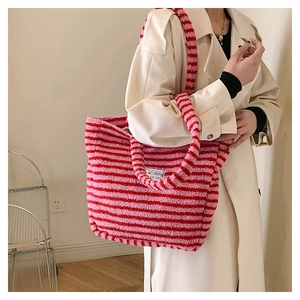 Dettaglio della borsa tote in peluche a righe rosse e rosa con tracolla e trench beige
