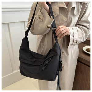 Minimalist black nylon crescent tote bag with woven cord zipper and adjustable strap