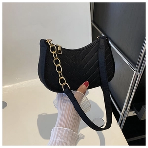 Close-up of black crescent felt bag with V-quilted texture and gold chain detail