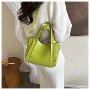 Detail of green glossy PU leather tote bag with vertical stitching and gold hardware