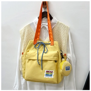 Bright yellow canvas bucket bag with orange straps and a mini round coin purse for travel