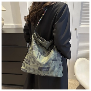 Detail of grey-green canvas bag featuring vintage newspaper print and rainbow letter strap