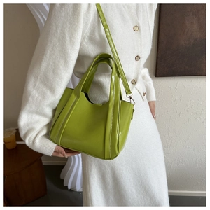 Close-up of lime green faux leather tote bag with shoulder strap on a model