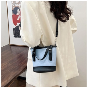 Model wearing a blue and black bucket bag with a white blazer for a stylish look
