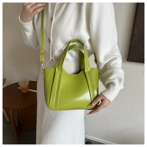 Lifestyle shot of an avocado green tote bag with adjustable strap on a female model