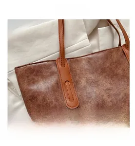 Close-up of the vintage cracked leather texture and strap stitching on brown tote bag