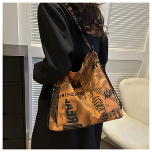 Detail of trendy orange and black tote bag with retro newspaper print and LOVE strap