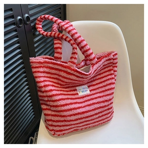 Borsa tote in peluche a righe rosa e bianche con texture morbida su una sedia