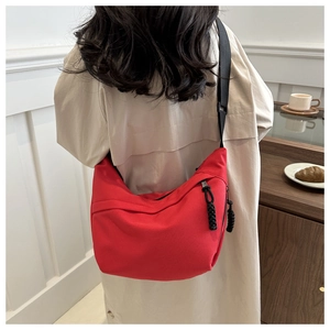 Detail of red nylon dumpling bag showing smooth texture and black adjustable strap