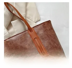 Close-up of durable reinforced stitching and retro leather texture on brown tote bag