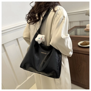 Detail of black PU leather tote bag with plush star pendant and fashion label on off-white coat