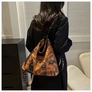 Close-up of orange vintage newspaper print bag with decorative wide LOVE woven strap