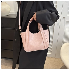 Detail of pink faux leather bucket bag showing wavy top edge and adjustable strap on model