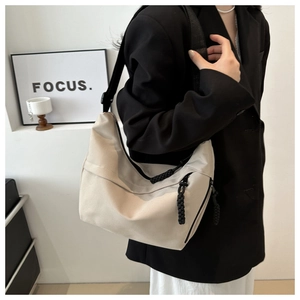 Detail of light beige canvas hobo bag with distinctive black woven rope zipper pulls