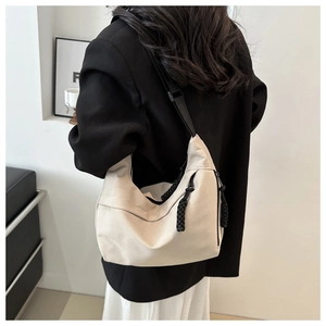 Detail of off-white nylon tote bag showing adjustable black strap and side zipper pocket