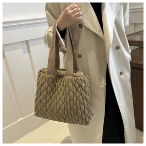 Detail der khakifarbenen Stepptasche mit welliger Textur und gewebten Tragegriffen