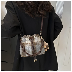 Detail of checkered wool bucket bag with drawstring closure and cute teddy bear charm