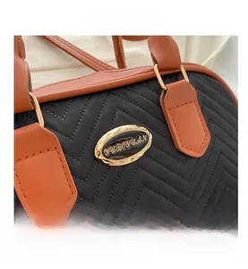 Close-up of V-quilted black nylon handbag with brown leather trim and gold metal hardware