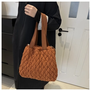 Detail einer caramel-farbenen Stepptasche mit Plissee-Struktur und breitem Tragegriff