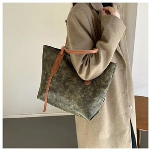Detail of vintage oil wax leather tote bag with brown straps and olive green texture