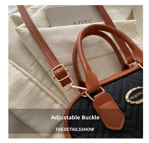 Detail of adjustable gold buckle and brown leather strap on a quilted black handbag