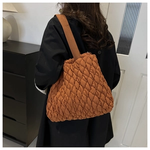 Detail einer braunen gesteppten Puffer-Tasche mit Rautenmuster und breitem Schultergurt