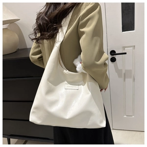White minimalist tote bag in glossy leather worn by model in a modern home interior