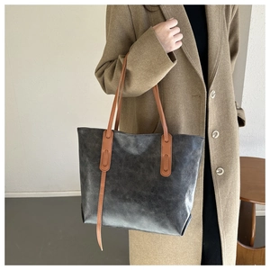 Detail of vintage oil leather tote bag with brown straps and textured dark finish