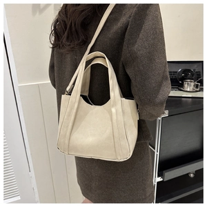 Side view of cream tote bag styled with dark blazer showing shoulder strap detail