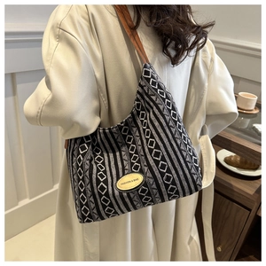 Détail d'un sac cabas tissé à carreaux avec bandoulière en cuir porté par un mannequin