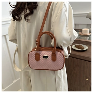 Detailed view of a pink V-quilted small handbag with brown handle on a wooden cafe table