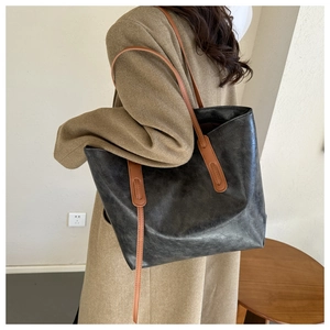 Detail view of the large vintage tote bag with thin leather straps on a camel wool coat