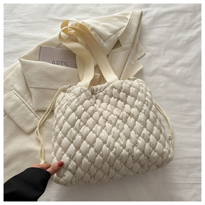 Nahaufnahme der cremefarbenen Stepptasche mit Kordelzug und weicher, gesteppter Textur