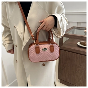Detail of pink quilted handbag with brown trim and adjustable crossbody shoulder strap