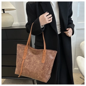 Brown vintage faux leather tote bag with smooth matte finish worn by model in black blazer