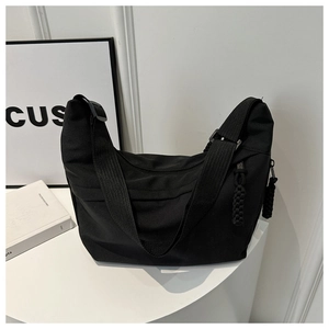 Detail view of a black crescent nylon tote bag with wide strap and woven knot zipper pull