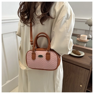 Detail of pink quilted mini crossbody bag with brown handles in cozy cafe setting