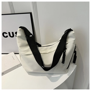 Detail of white nylon tote bag featuring black wide strap and woven cord zipper pull