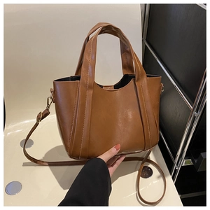 Detailed view of brown faux leather tote bag with vertical stitching and hand-held strap