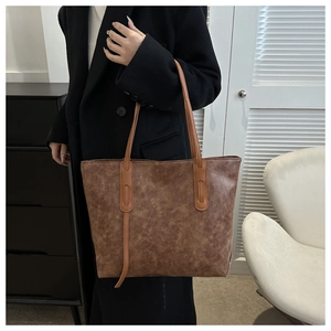 Detail of vintage brown leather tote bag with stylish stitching and long handles