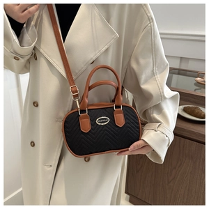 Macro detail of a mini quilted handbag featuring V-pattern stitching and brown leather trim