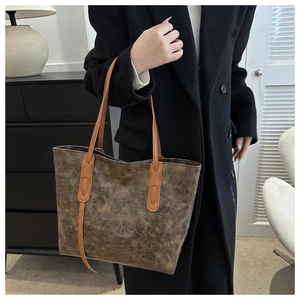 Detail of vintage tote bag in dark brown aged leather with light brown shoulder straps