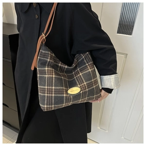 Détail du sac hobo vintage à carreaux avec texture laine et étiquette en cuir jaune