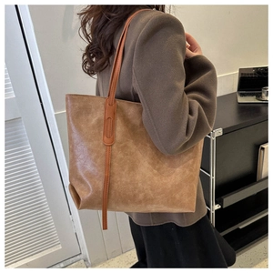 Detailed close-up of retro brown tote bag with oily leather texture and shoulder strap