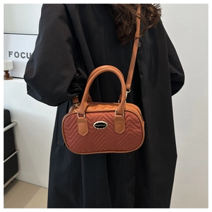 Model showing caramel brown V-quilted handbag with dual handles and long shoulder strap