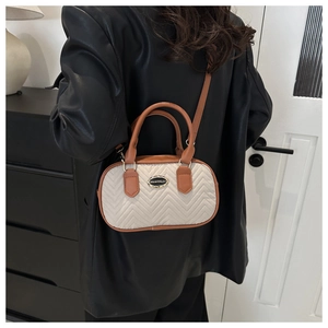 Detailed view of beige and brown crossbody bag featuring V-quilted fabric and metal logo
