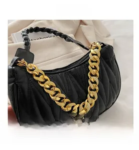 Detail view of V-shaped quilted black crescent bag with chunky gold chain and leather handle