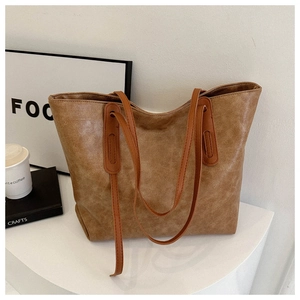 Detail of vintage brown leather tote bag showing textured finish and shoulder straps
