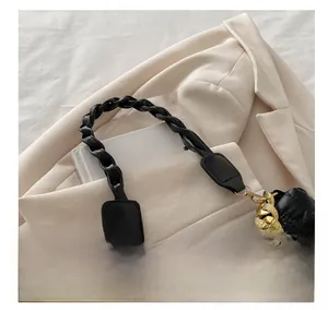 Detail of black quilted leather handbag with woven handle and rhinestone chain
