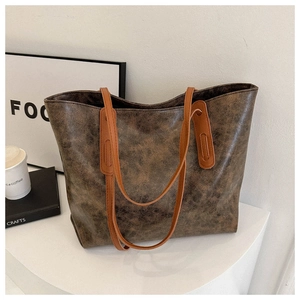 Deep brown vintage leather tote bag shown on a minimalist white stage with books